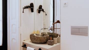 A bathroom with a stone sink, a towel rack, and a mirror.