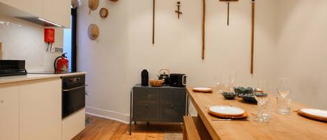 Une cuisine avec un plancher en bois, une table à manger dressée avec des assiettes et des verres, et divers appareils de cuisine.