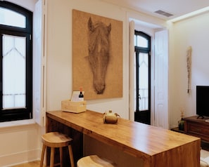 A wooden bar area with a large horse-themed artwork, a wine bottle, and a menu on the counter. - A Casa Brava (Santarém)