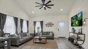 Ein modernes Wohnzimmer mit grauem Sofa, Couchtisch und Fernseher an der Wand.