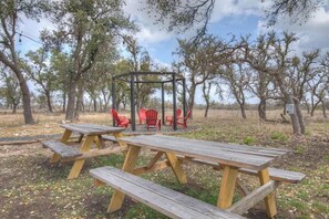 Ein Picknickplatz mit Holzbänken und roten Stühlen, umgeben von Bäumen.