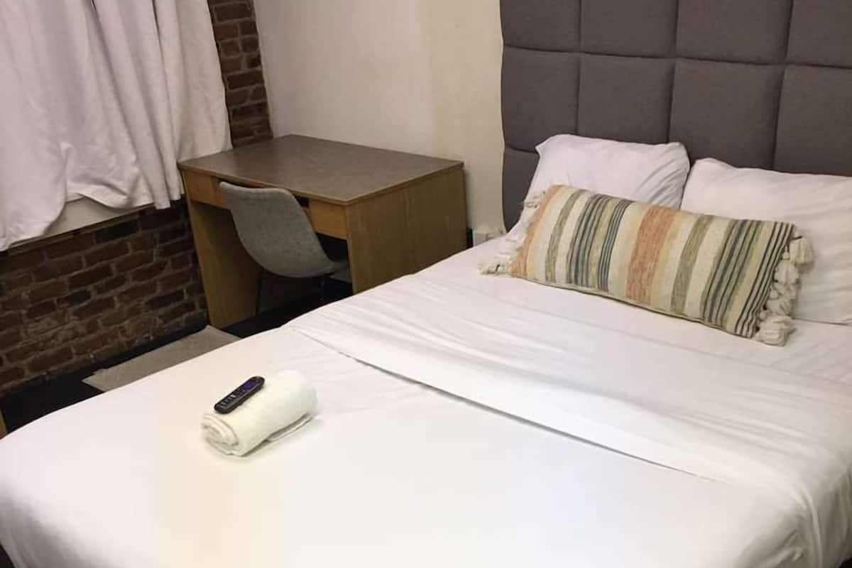 A hotel room with a bed, a desk, and a chair.
