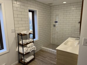 Een bad/douchecombinatie, handdoeken, zeep, toiletpapier