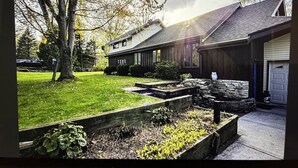 A residential property with a well-maintained lawn, a stone retaining wall, and a garage. - Road America Adjacent Lake House with indoor pool (Plymouth)