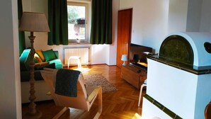 Un salon comprenant un canapé, un fauteuil, une table, une lampe, un radiateur et un gril.