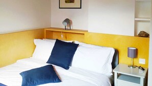 Une chambre à coucher avec un lit, une table de chevet, une lampe et un tableau encadré au mur.