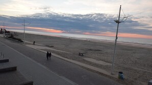 A paved walkway beside a beach with a clear sky and distant mountains. - Apartment (Coxyde)