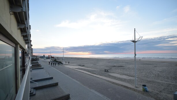 A coastal promenade with steps leading to the beach, benches, and a trash bin. - Apartment (Coxyde)