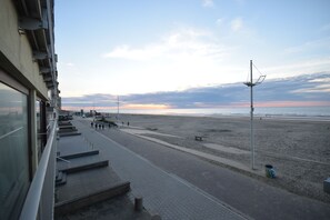 A coastal promenade with steps leading to the beach, benches, and a trash bin. - Apartment (Coxyde)