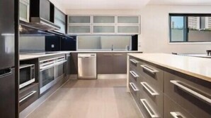 Een moderne keuken met roestvrijstalen apparatuur, een inbouwoven en een groot raam voor natuurlijk licht.
