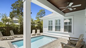 A pool area with two pools, lounge chairs, and a covered patio with a ceiling fan. - Stella Maris- Updated Home, Heated Private Pool, Walk to the Beach + Gulf Place! (Santa Rosa Beach)