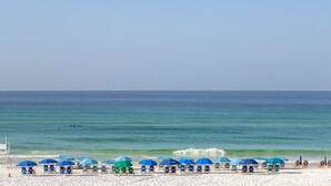 A beach with rows of blue and green umbrellas, beach chairs, and a lifeguard stand. - Stella Maris- Updated Home, Heated Private Pool, Walk to the Beach + Gulf Place! (Santa Rosa Beach)