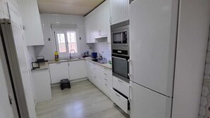 A kitchen with white cabinets, a microwave, and a refrigerator. - Charming villa with swimming pool, very well equipped and 900m from the beach (Torredembarra)