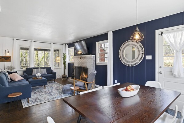 Una sala de estar con chimenea, una mesa de comedor y un espejo grande en la pared.