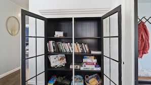 A room with a corner bookshelf containing books, magazines, and toys. - Private + Wooded + Quaint & Cozy + 5 mins to Dwntn Blk Mtn + 15 mins to Ashvle (Black Mountain)