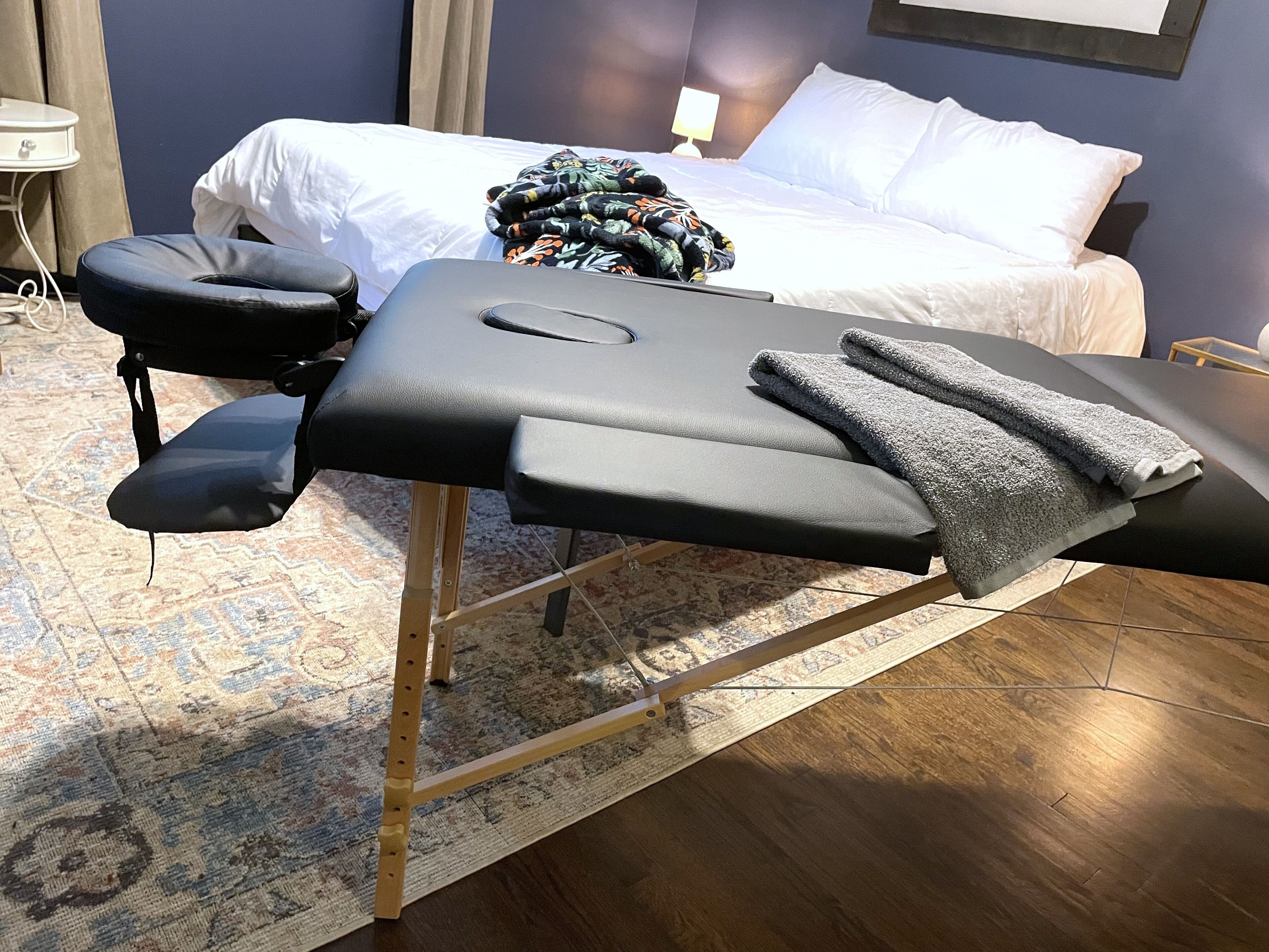 Ein Massagetisch mit Handtüchern und einem Stuhl in einem Hotelzimmer.