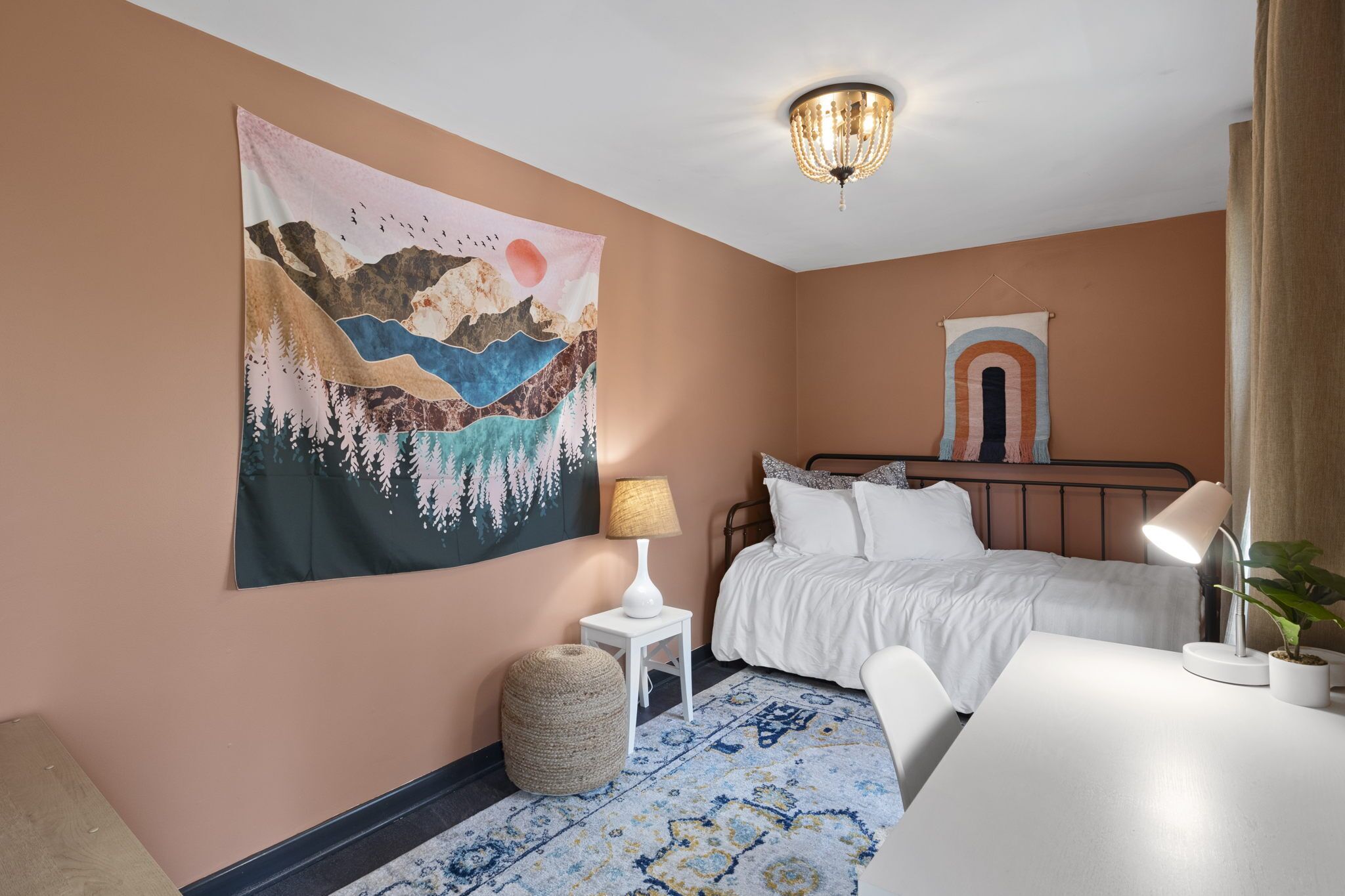 Ein Schlafzimmer mit Bett, Nachttisch, Lampe und Wandteppich.