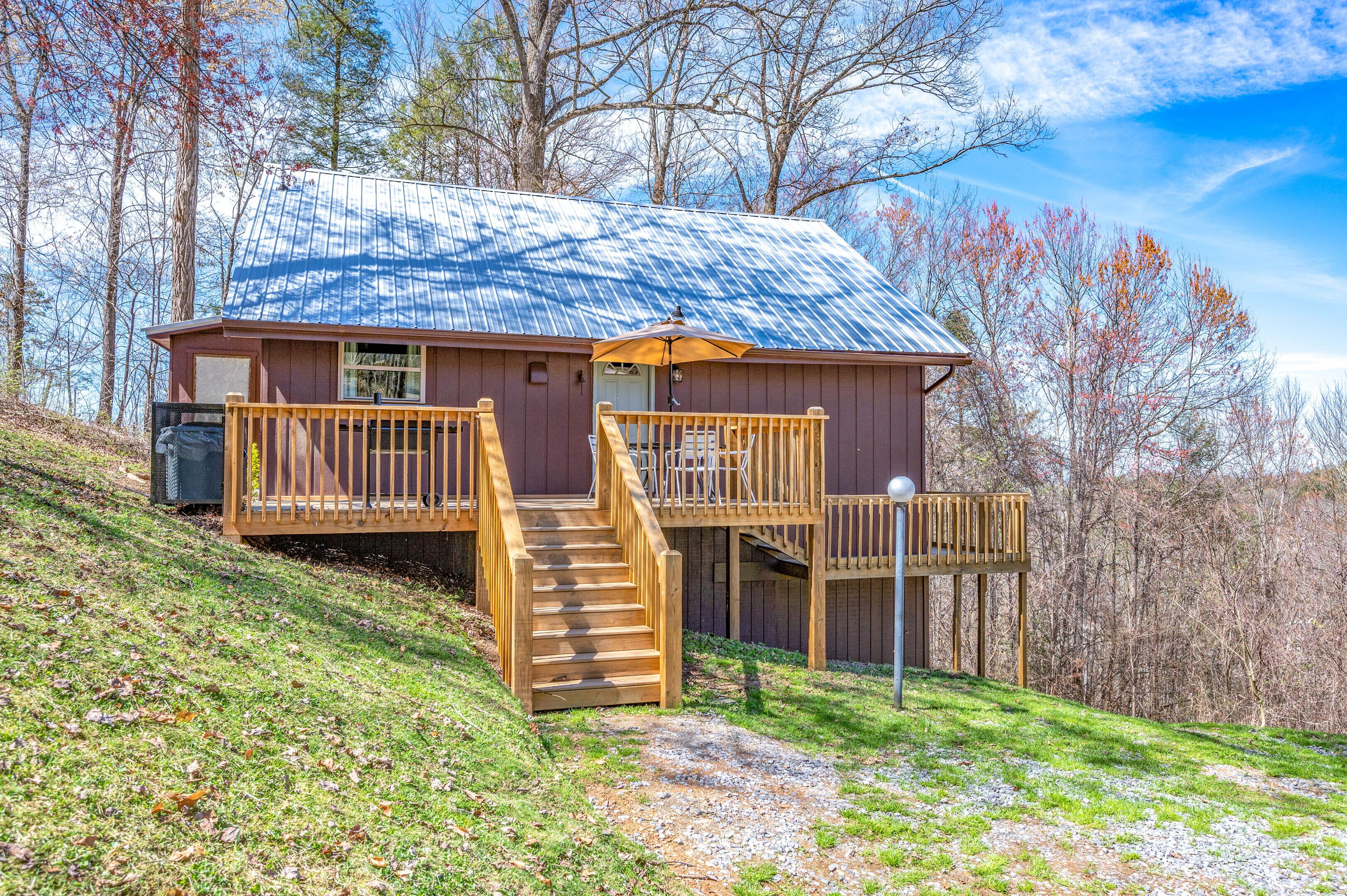 A cabin with a metal roof, wooden deck, and stairs leading to a porch.