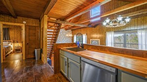 A wooden interior with a kitchen area, including a dishwasher, cabinets, and a staircase. - 🍁CLOSE TO GATLINBURG & PIGEON FORGE W/POOL TABLE🎱 (Gatlinburg)