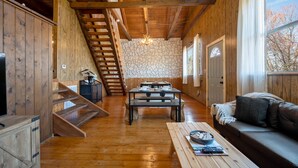 A wooden interior with a staircase, a stone wall, a dining table, a sofa, and a window with a view. - 🍁CLOSE TO GATLINBURG & PIGEON FORGE W/POOL TABLE🎱 (Gatlinburg)