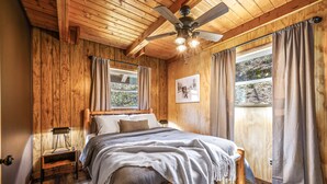 A wooden-paneled bedroom with a bed, a ceiling fan, and two windows with curtains. - 🍁CLOSE TO GATLINBURG & PIGEON FORGE W/POOL TABLE🎱 (Gatlinburg)