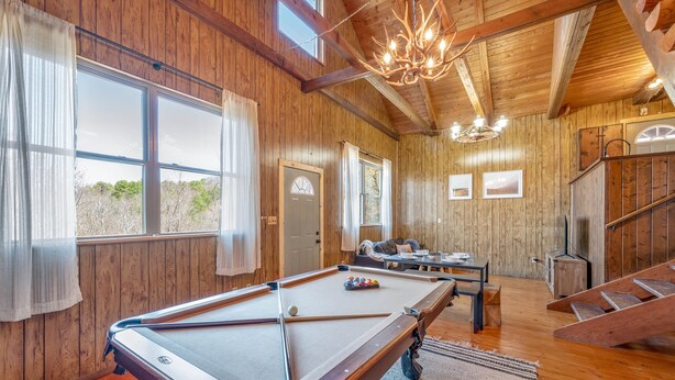 A wooden interior with a pool table, a staircase, and a view of the outdoors. - 🍁CLOSE TO GATLINBURG & PIGEON FORGE W/POOL TABLE🎱 (Gatlinburg)