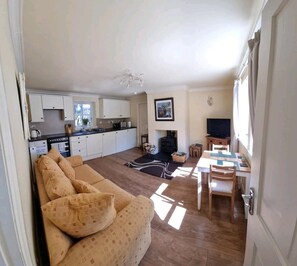Un espacio habitable compacto con kitchenette, un sofá, una mesa de comedor y una televisión.