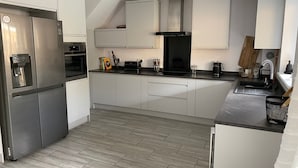 Een moderne keuken met roestvrijstalen apparatuur, witte kasten en een visgraatvloer.