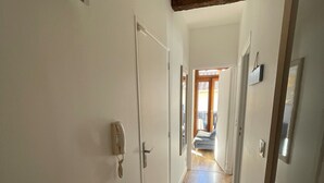 Ein Flur mit Holzboden, weißen Wänden und einer Tür links.