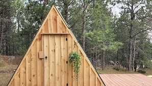 Una cabaña de madera con techo triangular, una puerta de madera y un pequeño porche.