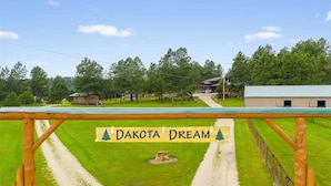 Entorno rural con un letrero que dice "Dakota Dream" y un sendero de tierra que conduce a un edificio.