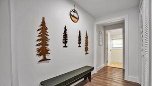 A hallway with a wooden bench, a wall-mounted sign, and several tree-shaped decorations.