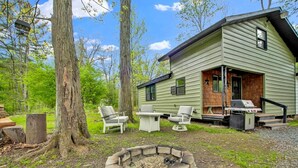A cabin with a fire pit, outdoor seating, and a grill.