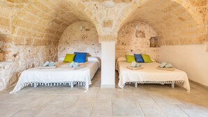 A room with two beds, stone walls, and a tiled floor.
