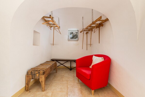 A room with a red chair, a wooden bench, and a small window with a view.