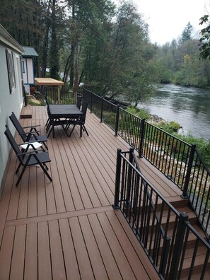 A wooden deck with a table and chairs, overlooking a river. - Cozy Cottage right on the McKenzie River! (Vida)