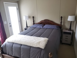 A bedroom with a bed, two bedside tables, a door, and a window.