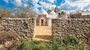 A stone-walled building with a tiled entrance and conical roofs. - Trullo Palma by Perle di Puglia (San Michele Salentino)