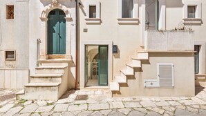 A building with a stone staircase leading to a door, a small window, and a door with a glass panel. - Casa Chianchizze by BarbarHouse (Ceglie Messapica)