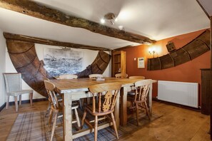 Cozy dining area with a wooden table and six chairs, surrounded by exposed beams and a large abstract painting.