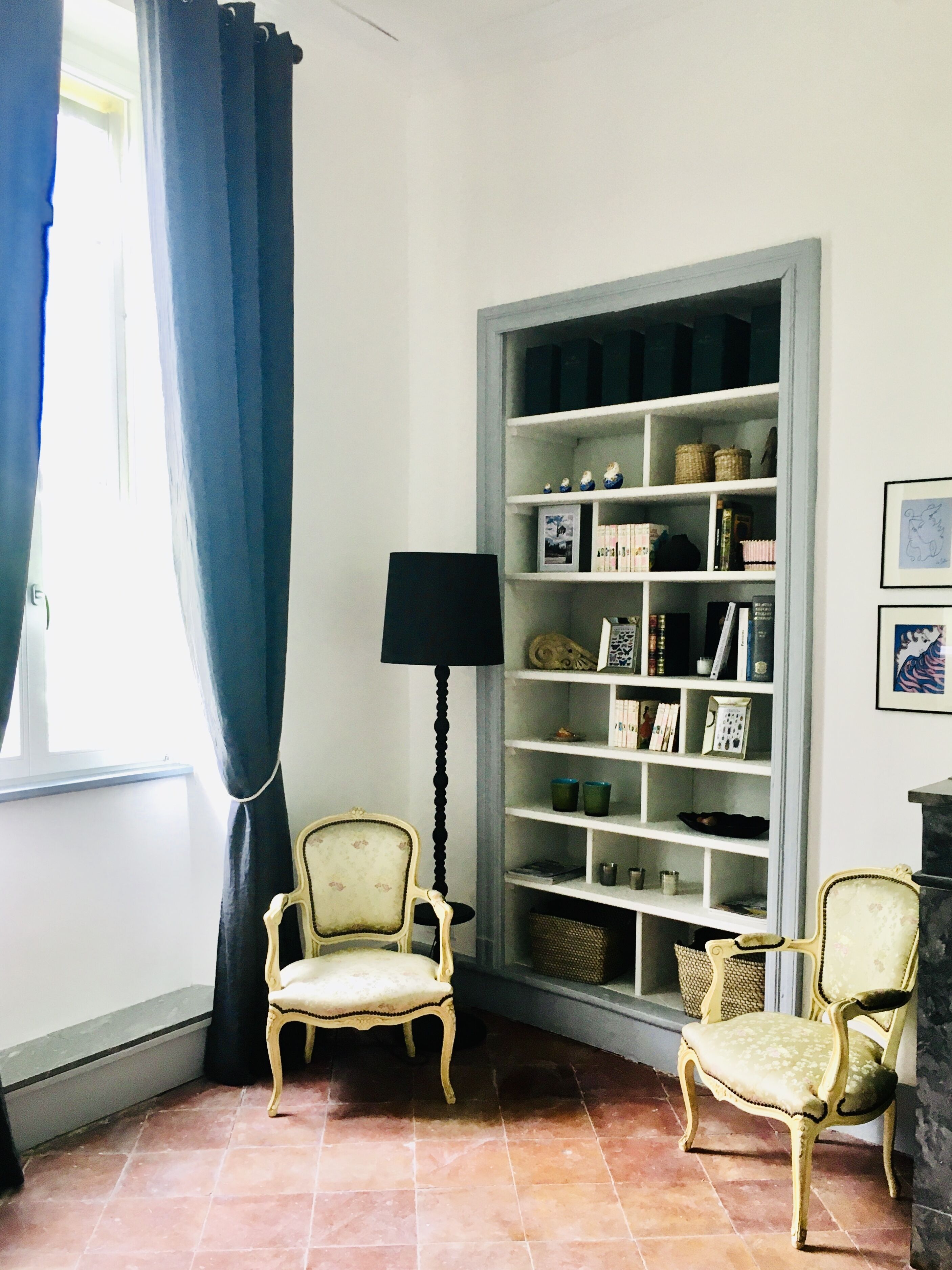 Quarto com duas cadeiras, uma estante e uma luminária.