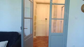 An open door leading to a bathroom with a shower and a white door.