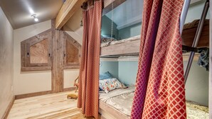 Una habitación con piso de madera, camas literas y una ventana con marco de madera.
