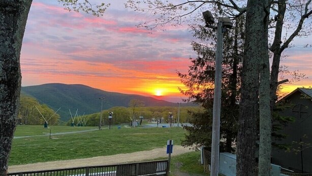 Une vue sur le coucher de soleil depuis un parc, avec un banc et des arbres.