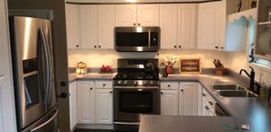 Una cocina moderna con electrodomésticos de acero inoxidable, armarios blancos y horno empotrado.