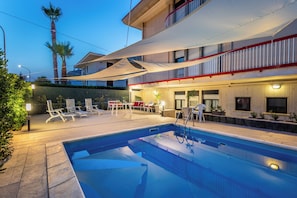 A swimming pool with lounge chairs and a covered patio area.