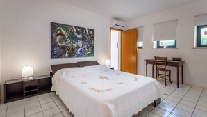 Ein Schlafzimmer mit Bett, Schreibtisch, Stuhl, Nachttisch, Lampe und einem Bild an der Wand.