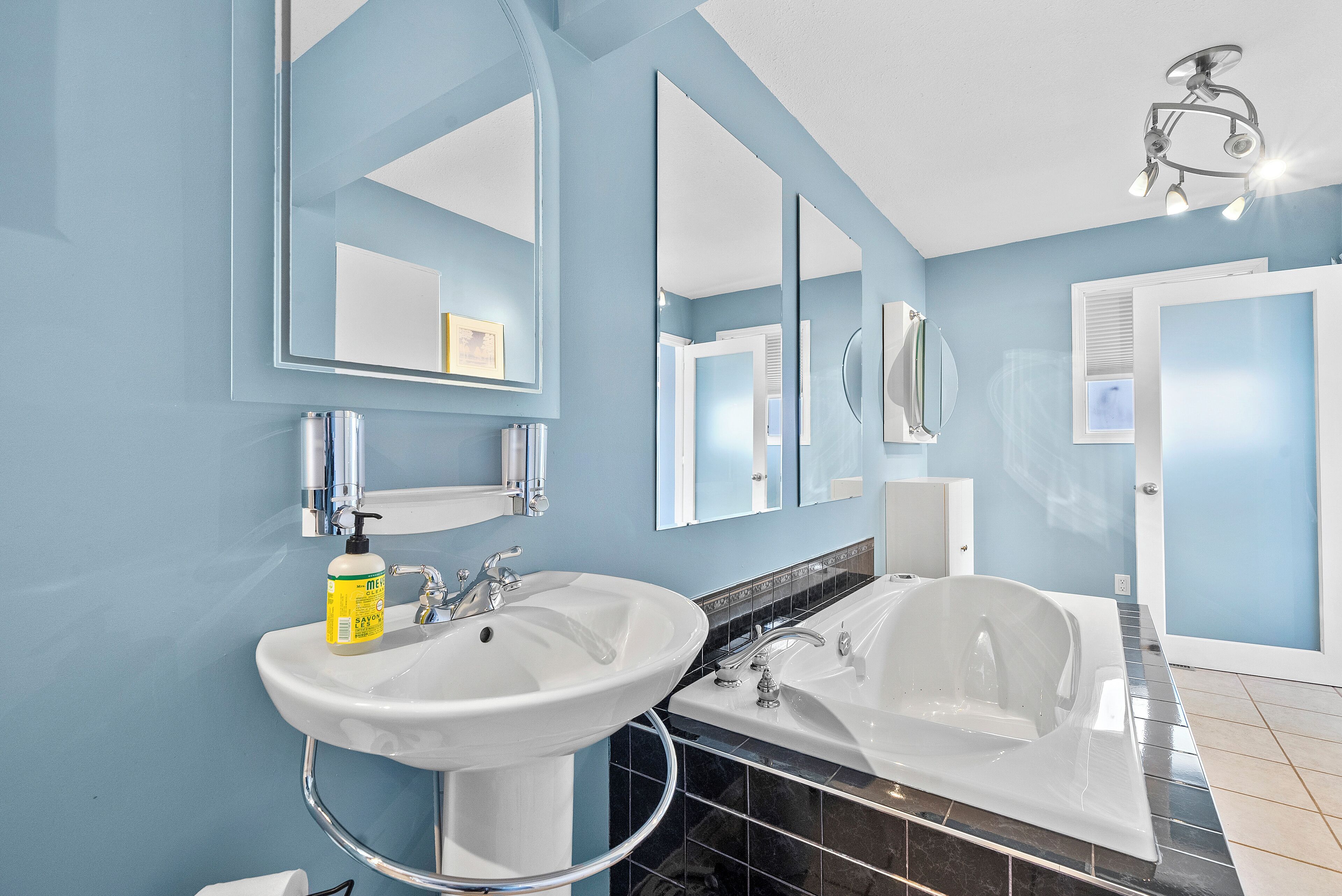A bathroom with two sinks, a bathtub, and a mirror.