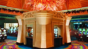 Un casino con una lámpara de araña grande y elaborada y una alfombra colorida.