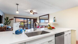 Une cuisine moderne dotée d’un grand îlot central, d’un lave-vaisselle et d’un ventilateur de plafond.